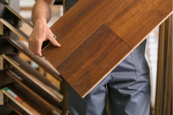 man holding hardwood | Clark Dunbar Flooring Superstore