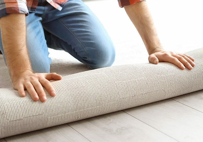 Man rolling out new carpet flooring in room | Clark Dunbar Flooring Superstore