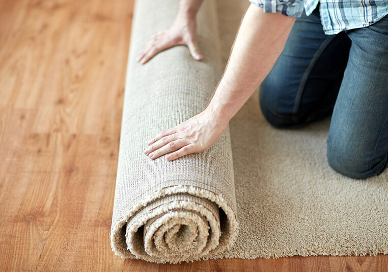 close up of male hands rolling carpet | Clark Dunbar Flooring Superstore