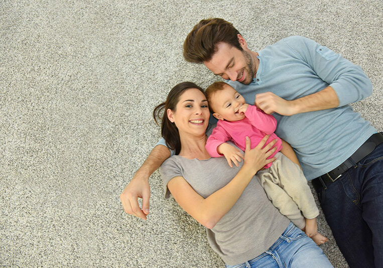 Upper view of family of three laying on carpet | Clark Dunbar Flooring Superstore